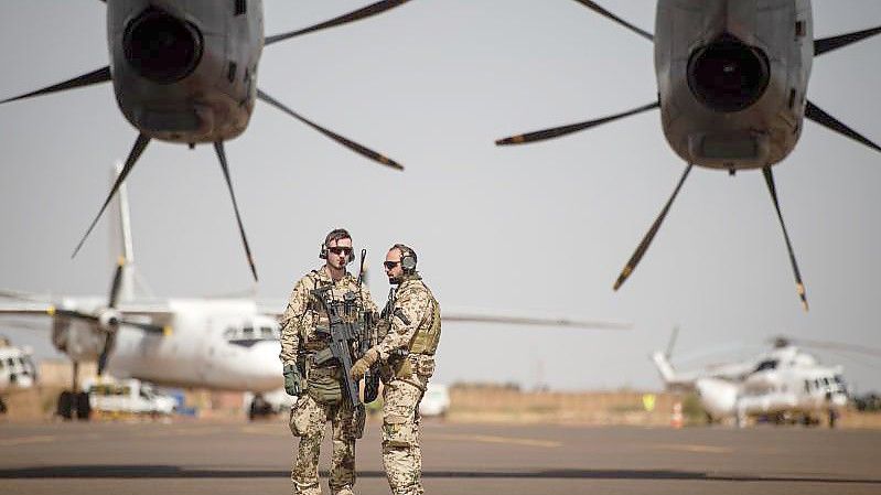 Deutsche Soldaten stehen am Flughafen in Gao und sichern ein Transportflugzeug. Foto: Arne Immanuel Bänsch/dpa