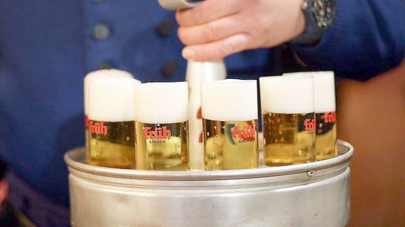 Ein Köbes (Kellner) trägt Kölsch-Bier aus. Das Oberlandesgericht Düsseldorf hat über die Einsprüche von drei Kölsch-Brauereien gegen Bierkartell-Bußgelder entschieden. Foto: picture alliance / dpa