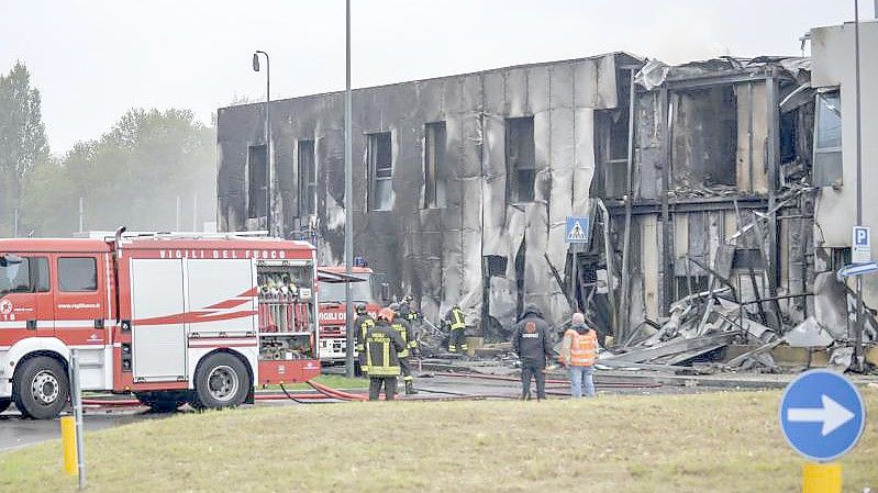 Feuerwehrleute stehen an der Unfallstelle, nachdem ein Leichtflugzeug kurz nach dem Start abgestützt und in ein leerstehendes Bürogebäude gekracht ist. Foto: Claudio Furlan/LaPresse/AP/dpa