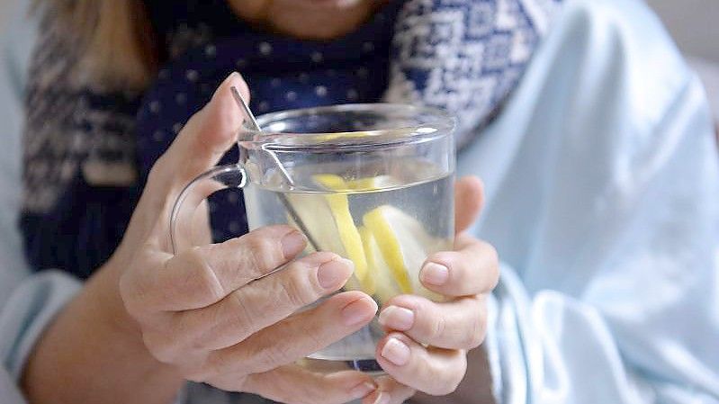 Eine Frau hält eine Tasse mit heißer Zitrone in ihren Händen. Foto: picture alliance / dpa