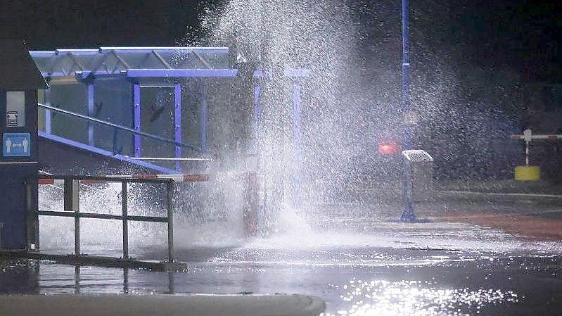 Die Gischt der Nordsee spritzt in der Nacht auf die zum Teil überflutete Mole des Fähranlegers in Dagebüll. Foto: Bodo Marks/dpa