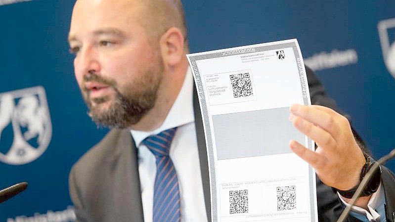 Andreas Brück, Staatsanwalt bei der Zentral- und Ansprechstelle Cybercrime (ZAC NRW), mit einem Paper Wallet für Bitcoin. Foto: Marius Becker/dpa