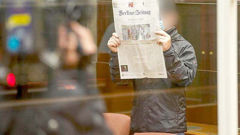 Der Angeklagte hält sich eine Zeitung vors Gesicht, während er zum Prozessbeginn in den Gerichtssaal im Berliner Kammergericht kommt. Foto: Jörg Carstensen/dpa