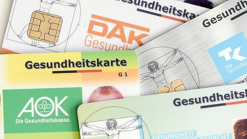 Gesundheitskarten verschiedener Krankenkassen liegen auf einem Tisch. Foto: Jens Kalaene/ZB/dpa