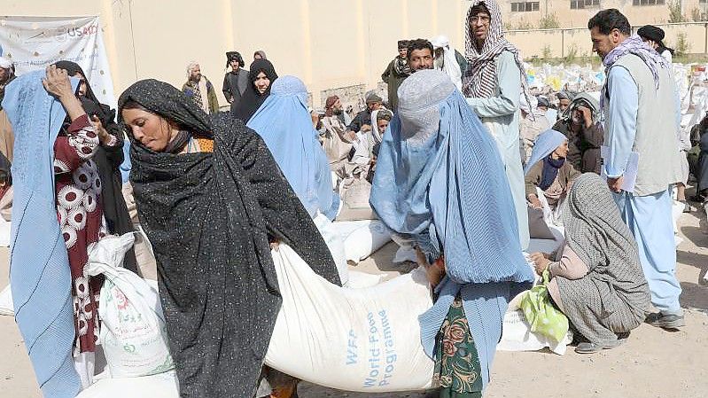 Frauen verlassen eine Verteilungsstelle des Welternährungsprogramm WFP am Stadtrand mit Lebensmittelrationen. Die Rationen bestehen aus Weizenmehl, Erbsen, Öl und Salz für jede Familie. Foto: Marco Di Lauro/World Food Programm WFP/dpa