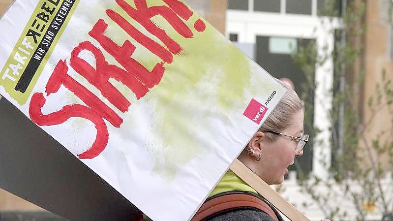 Eine Frau hält ein Schild hoch auf dem „Streik!“ steht. Foto: Mona Wenisch/dpa