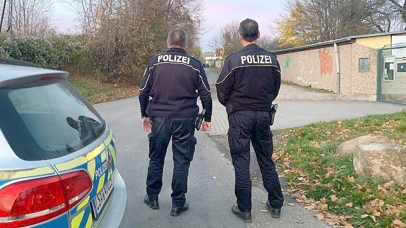 Polizisten vor dem Bereich eines Tatorts in einem Garagenkomplex, in dem die tote 14-Jährige gefunden worden ist. Foto: Thomas Schulz/dpa