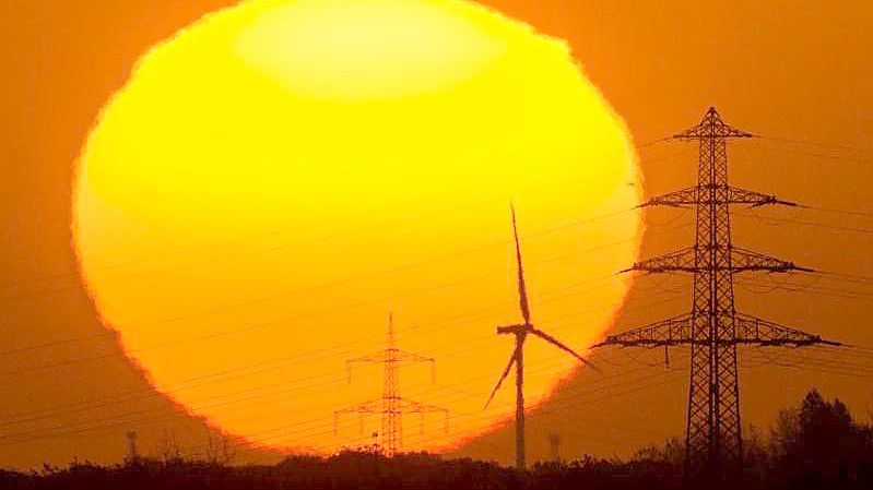 Die Sonne geht hinter Windrädern und Hochspannungsleitungen in der Region Hannover auf. Foto: Julian Stratenschulte/dpa