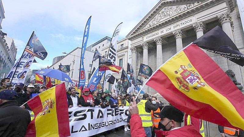 Polizisten laufen während des Protestmarsches am spanischen Parlament in Madrid vorbei. Foto: Paul White/AP/dpa