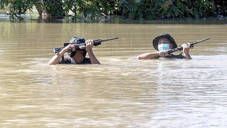 Zwei Soldaten waten durch eine überflutete Straße. Foto: Zulkarnain Kamaruddin/BERNAMA/dpa