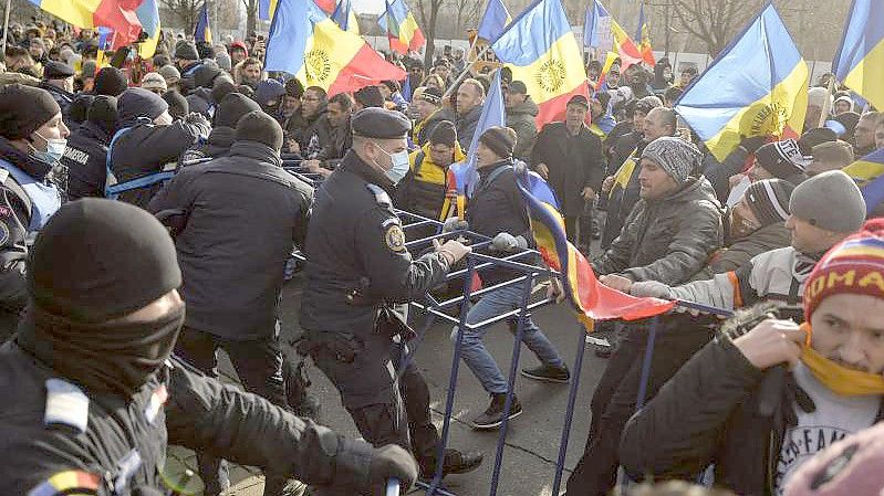 Polizisten der Bereitschaftspolizei ringen vor dem Parlamentspalast in Bukarest mit Demonstranten. Foto: Alexandru Dobre/AP/dpa