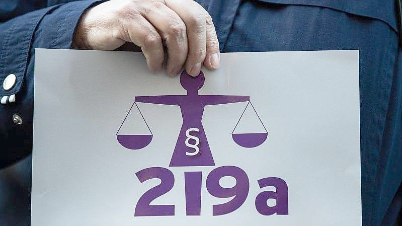 Eine Frau hält bei einer Kundgebung einen Zettel mit der Aufschrift „219a nicht zeitgemäß!“. Foto: Silas Stein/dpa