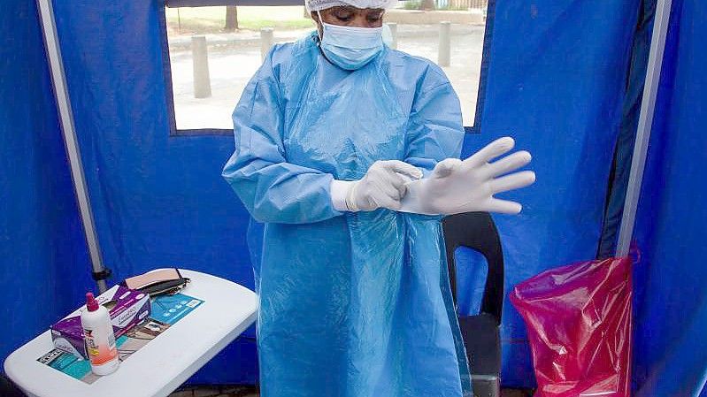 Ein Mitarbeiter des Gesundheitswesens in Südafrika bereitet sich auf einen Corona-Test vor. Foto: Denis Farrell/AP/dpa