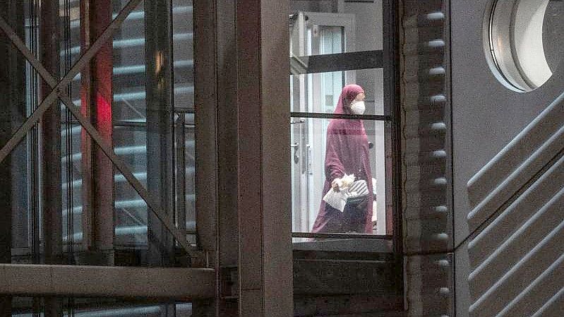 Eine verschleierte Frau mit Mund-Nasen-Bedeckung verlässt eine Chartermaschine und betritt einen abgeschirmten Bereich der Bundespolizei am Flughafen Frankfurt. Foto: Boris Roessler/dpa