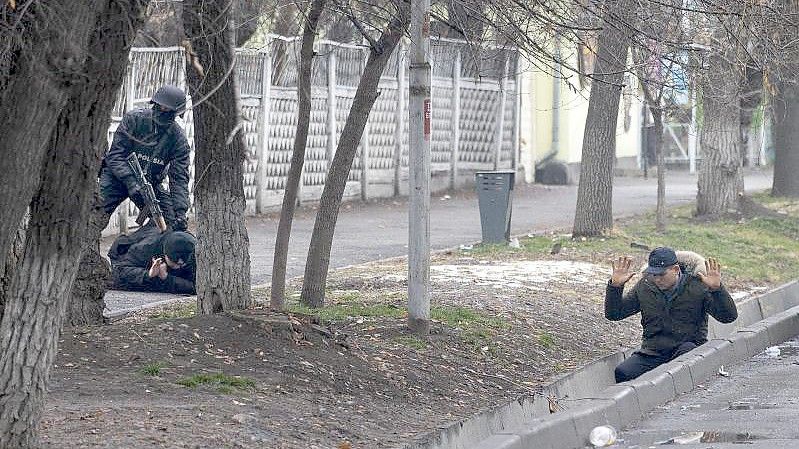 Ein bewaffneter Bereitschaftspolizist im kasachischen Almaty hält während einer sogenannten Anti-Terror-Operation zwei Demonstranten fest. Foto: Vasily Krestyaninov/AP/dpa