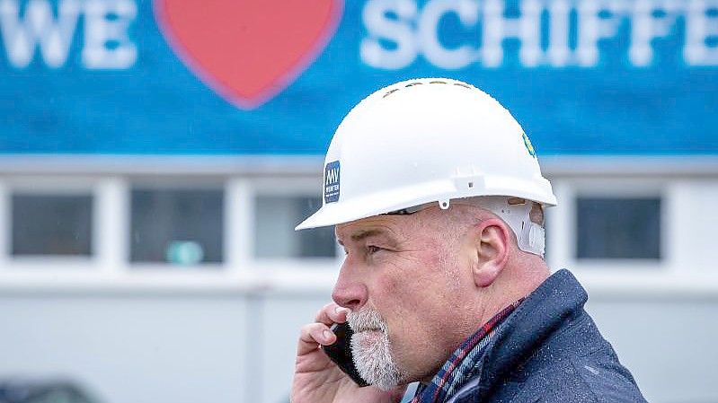 Ines Scheel, Betriebsrätin der MV-Werften, und Schiffbauer stehen mit einem Transparent der IG Metall am Haupteingang zur MV Werft in Wismar. Foto: Jens Büttner/dpa-Zentralbild/dpa