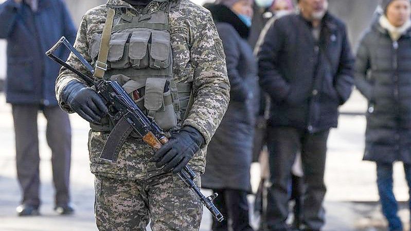 Ein kasachischer Soldat patrouilliert in Almaty nahe einer Polizeistation. Hinter ihm versammeln sich Angehörige von Personen, die nach den Protesten gegen die Regierung verhaftet wurden. Foto: Sergei Grits/AP/dpa