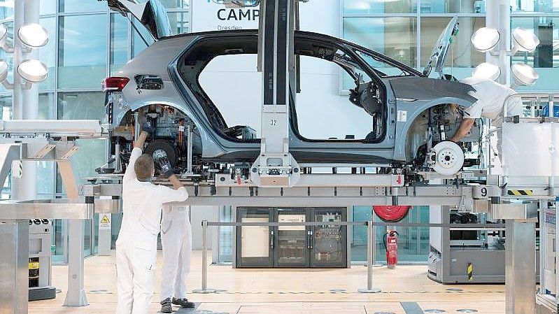 VW-Mitarbeiter montieren im Rahmen eines Presserundgangs in der Gläsernen Manufaktur von Volkswagen in Dresden bei der sogenannten Hochzeit die Karosserie und den Antriebsstrang eines VW ID.3. Foto: Sebastian Kahnert/dpa-Zentralbild/dpa