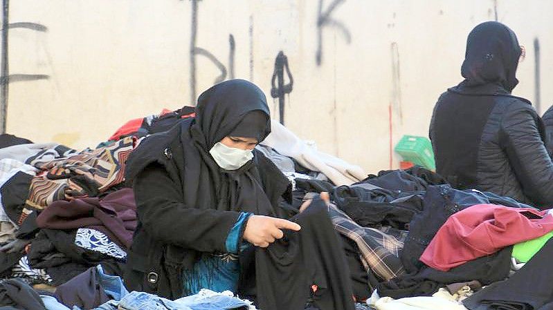 Eine Kundin schaut sich gebrauchte Kleidungsstücke auf einem zentralen Markt in Tunesiens Hauptstadt an. Foto: Cindy Riechau/dpa