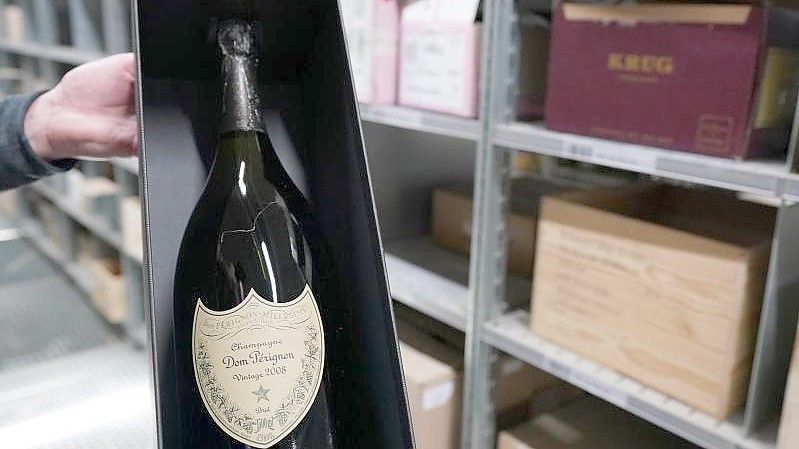 Ein Mitarbeiter hält eine Champagne-Flaschen des Weinhändlers Hawesko in der Hand. Foto: Marcus Brandt/dpa/Symbolbild