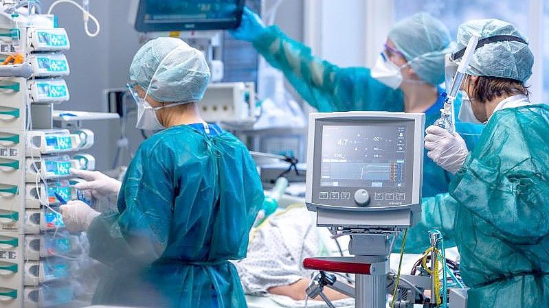 Ärzte und Pflegekräfte betreuen Patienten in einem der Behandlungszimmer der Intensivstation in der Universitätsmedizin Rostock. Foto: Jens Büttner/dpa-Zentralbild/dpa