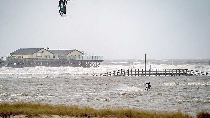 Sankt Peter-Ording: Ein Kitesurfer zieht in dem vom Wind aufgepeitschten Meer seine Bahnen (Archivbild). Foto: Axel Heimken/dpa