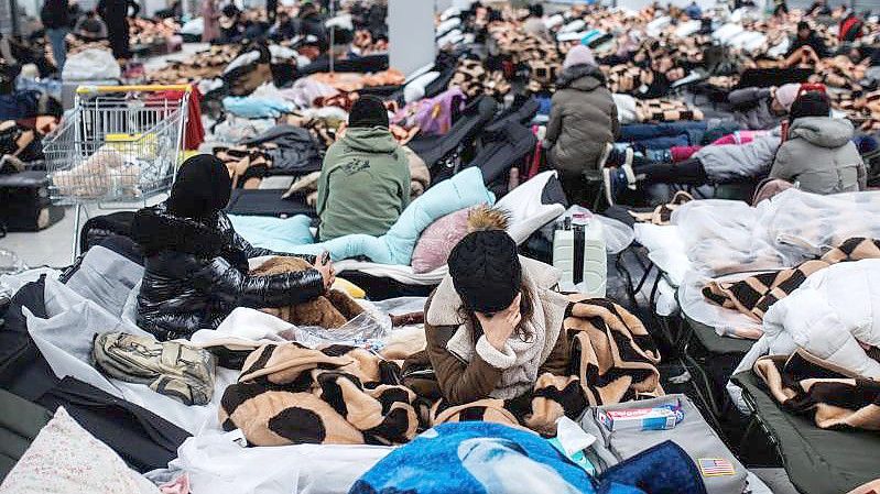 Menschen ruhen sich in einem Einkaufszentrum in Mylny aus, das für die vorübergehende Aufnahme von Flüchtlingen aus der Ukraine bestimmt ist. Foto: Alejandro Martínez Vélez/EUROPA PRESS/dpa