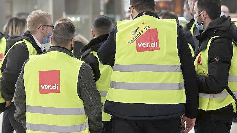 Eine Gruppe Streikender mit gelben Verdi-Westen versammelt sich im Köln-Bonn-Airport (Februar). Foto: David Young/dpa