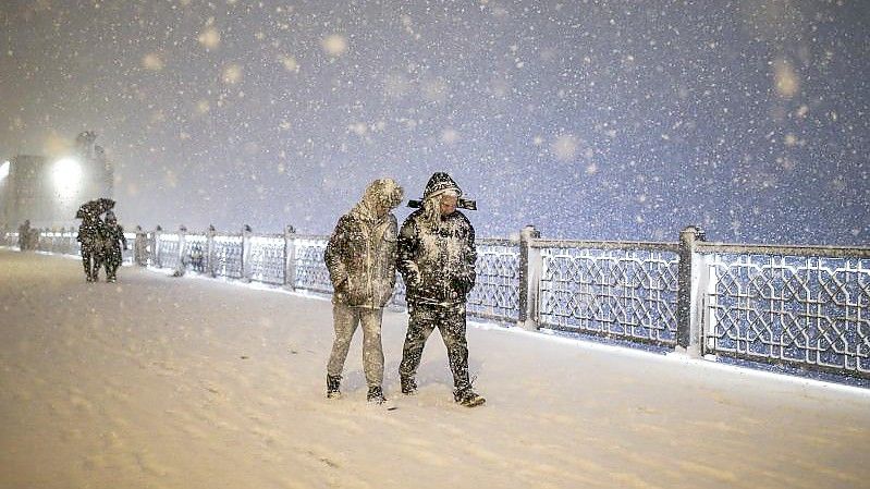 Fußgänger laufen bei Schneefall über die Galata-Brücke in Istanbul. Foto: Emrah Gurel/AP/dpa