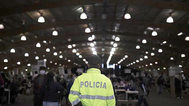 Ein Polizist in Kolumbiens Haupstadt Bogotá beobachtet das Geschehen in einem Wahllokal. Foto: Ivan Valencia/AP/dpa