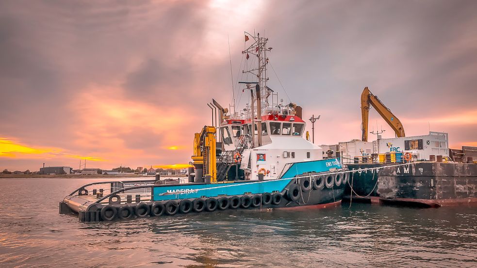 Voll im Einsatz: Die „Ems Tug“ schiebt einen Bagger-Ponton im Abendrot. Foto: Malech