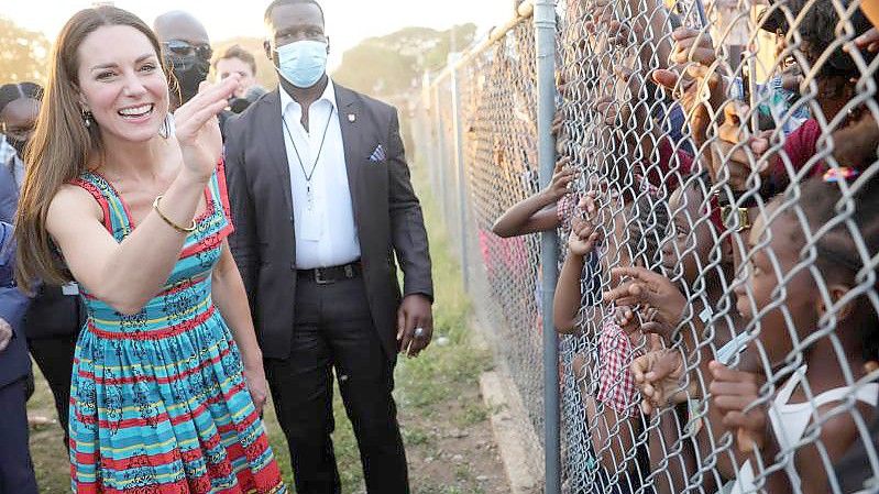 Die Herzogin von Cambridge winkt Kindern während eines Besuchs in Trench Town, dem Geburtsort des Reggae in Kingston, Jamaika, am vierten Tag ihrer Tour durch die Karibik im Namen der Königin anlässlich ihres Platinjubiläums zu. Foto: Chris Jackson/PA Wire/dpa