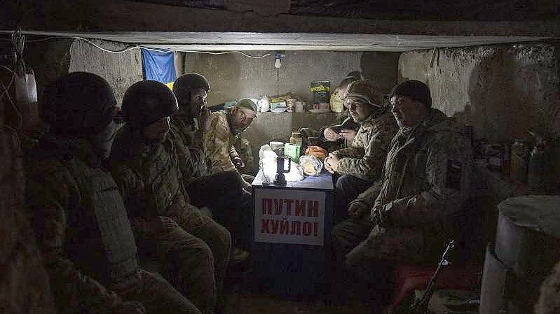 Ukrainische Soldaten sitzen in einem Armeegraben in den Außenbezirken von Mykolajiw. Foto: Petros Giannakouris/AP/dpa