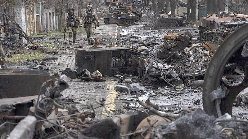 Zwei ukrainische Soldaten inspizieren in Butscha eine mit zerstörten russischen Militärfahrzeugen übersäte Straße. Foto: Rodrigo Abd/AP/dpa