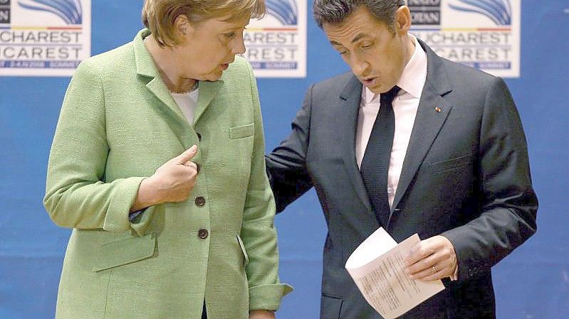 Die damalige Bundeskanzlerin Angela Merkel (l, CDU) spricht mit Nicolas Sarkozy, damals Präsident von Frankreich, am Ende der Eröffnungssitzung des NATO-Gipfels. Foto: Robert Ghement/epa/dpa