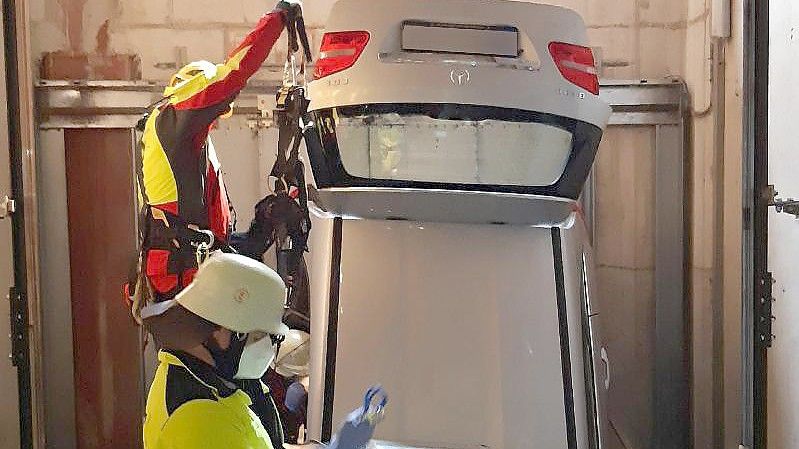 Ein Auto steckt in einem Aufzugschacht einer Tiefgarage in München. Foto: Feuerwehr/Feuerwehr München/dpa