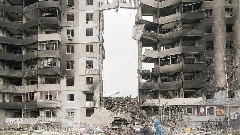 Frauen tragen ihre Lebensmittel an einem zerstörten Wohnhaus in Borodjanka vorbei. Foto: Vadim Ghirda/AP/dpa