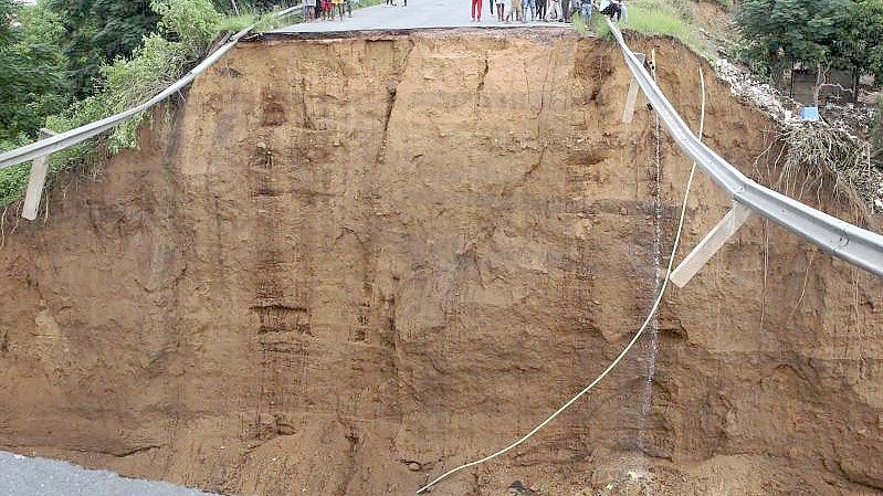 Menschen stehen nach ungewöhnlich heftigen Niederschlägen vor einer weggeschwemmten Brücke in Durban. Foto: Uncredited/AP/dpa