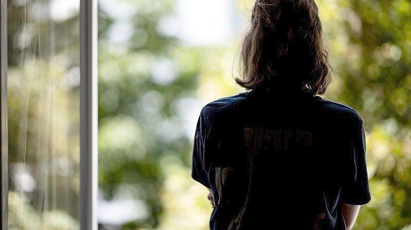 Eine Frau steht in ihrer Wohnung an einem Fenster. Foto: Fabian Sommer/dpa