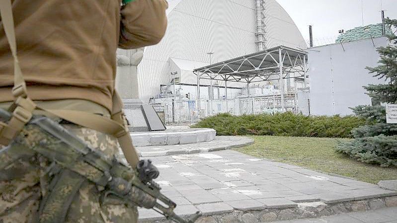 Ein ukrainischer Soldat steht vor dem Sarkophag, der den explodierten Reaktor im Kernkraftwerk Tschernobyl abdeckt. Foto: Efrem Lukatsky/AP/dpa