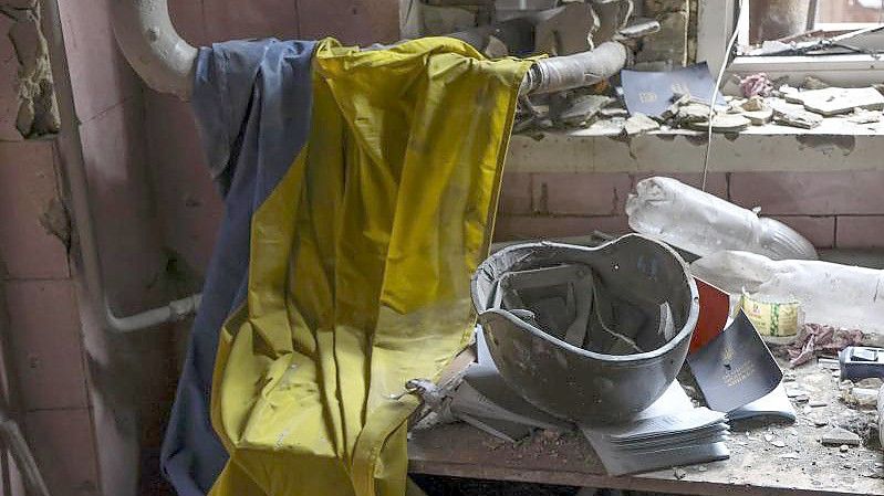 Eine ukrainische Flagge, ein Militärhelm und Dokumente liegen auf einem Tisch in einem zerstörten Teil einer Fabrik in Mariupol. Foto: Alexei Alexandrov/AP/dpa