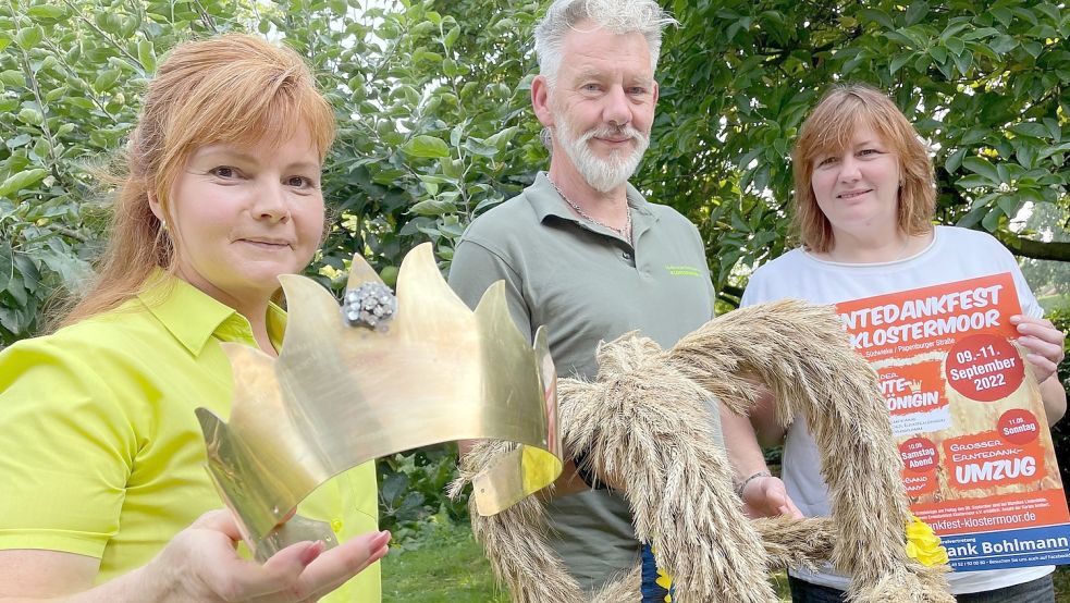 Christa Hoffschnieder (von links) mit der Krone der Erntekönigin, Joachim und Gunda Karles – mit kleiner Erntekrone und Plakat – freuen sich schon auf das dreitägige Spektakel. Foto: Janßen