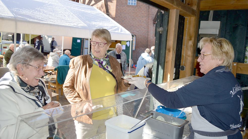 Der Verkauf von Bratkartoffeln mit Matjes war der Renner. Gesa Poelmann vom Möhlenkring Rhaude-Holte bedient einige Gäste. Foto: Weers