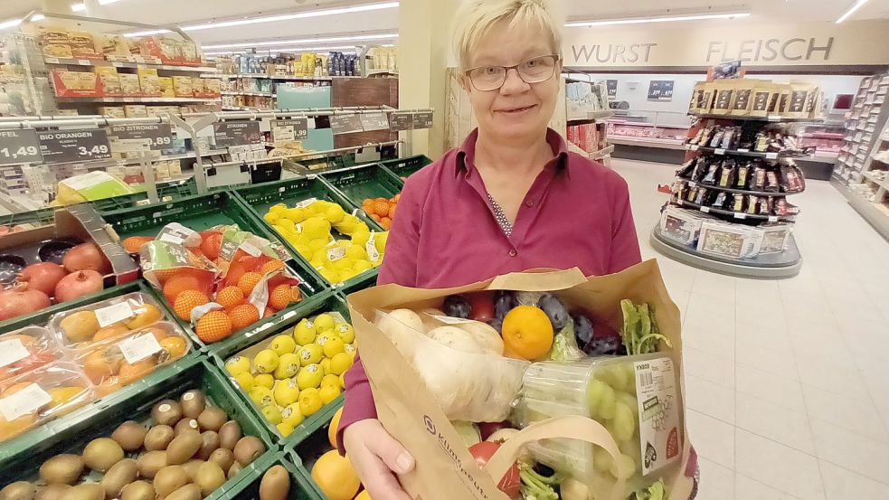 Hannelore Maas, Edeka-Mitarbeiterin in Jemgum zeigt eine der Tüten, mit Obst und Gemüse, das Kundinnen und Kunden retten können. Foto: Vogt