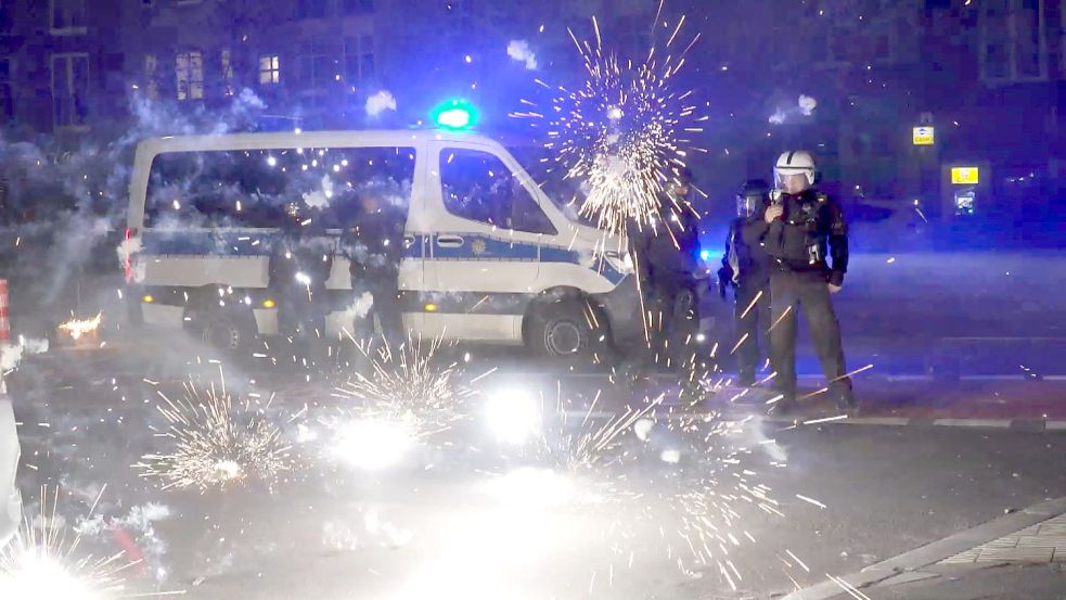 Polizeibeamte stehen hinter explodierendem Feuerwerk. Nach Angriffen auf Einsatzkräfte in der Silvesternacht hat die Diskussion um Konsequenzen begonnen. Foto: dpa/TNN