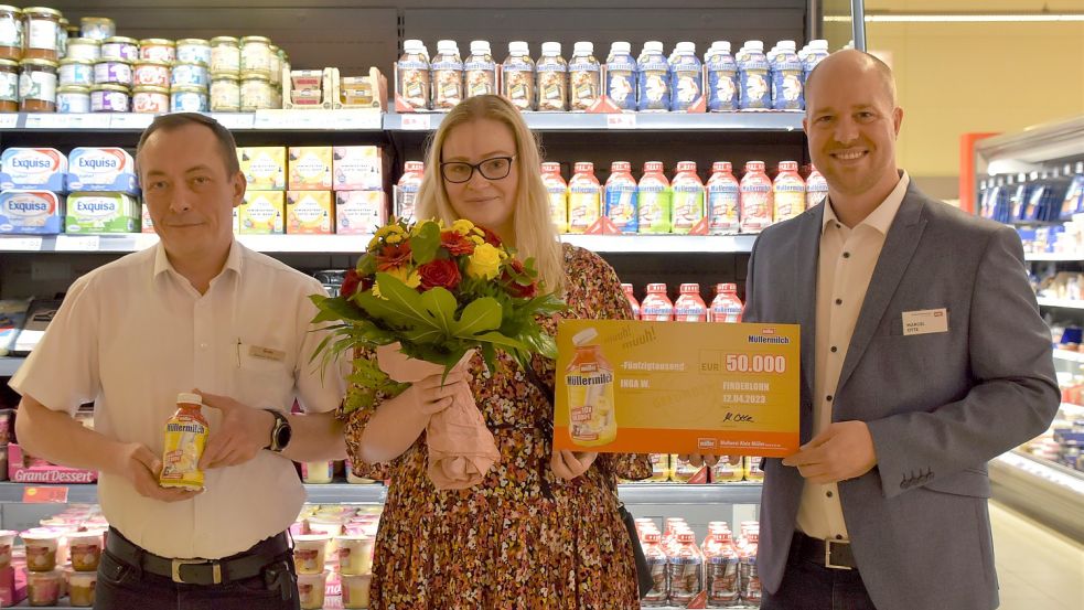 Blitzlichtgewitter vor dem Kühlregal: Famila-Filialleiter Alexander Heckmann (links) hält die muhende Flasche, während Müller-Außendienstmitarbeiter Marcel Otte den Scheck an Gewinnerin Inga-Louiza Wilmsmann überreicht. Foto: Hahn