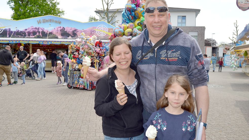 Moni, Mario und die achtjährige Anna Seemann aus Rhauderfehn genießen ein Softeis auf dem Rummelplatz.