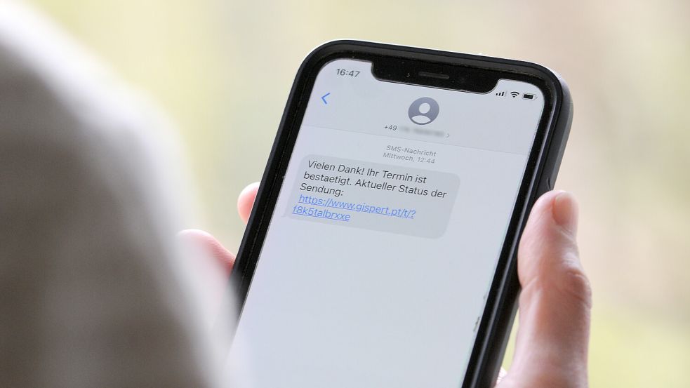 Eine Frau hält ein Smartphone in ihrer Hand, auf dessen Display eine Betrugs-SMS zu lesen ist. Die Aktionen von Cyber-Kriminellen gefährden in Deutschland nicht nur Wirtschaftsunternehmen und öffentliche Einrichtungen, sondern betreffen auch viele Privatpersonen. Foto: Wolf von Dewitz/dpa