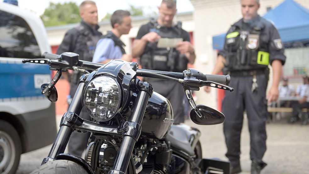 Die Polizisten sammeln eifrig die Geldscheine zusammen, die ein Motorradfahrer verloren hatte. Foto: dpa/Michael Bahlo