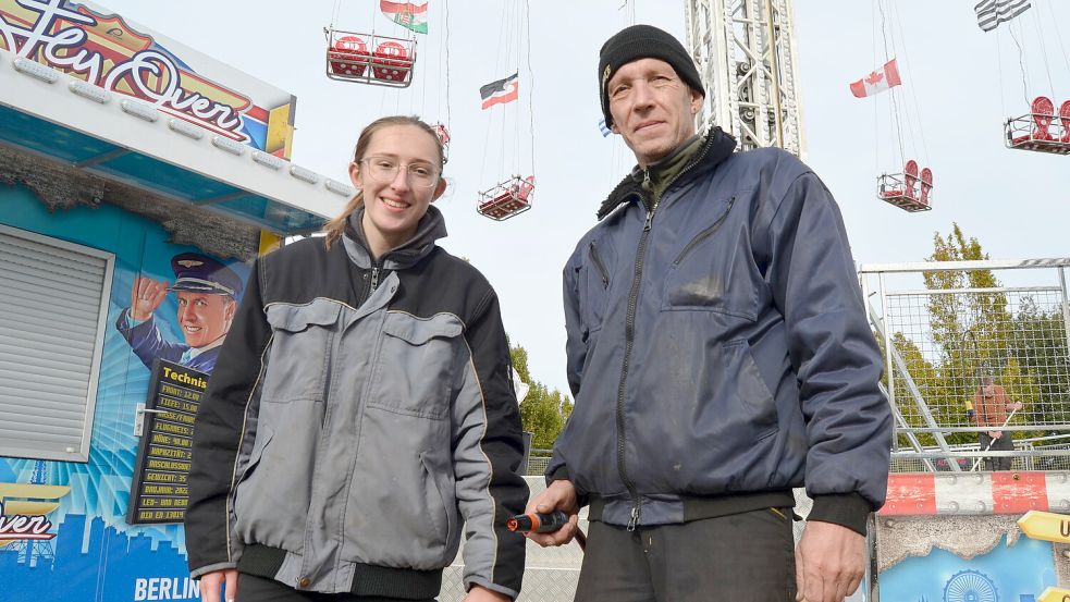 Leonie Leykum und ihr Kollege Andreas Kraus stehen hier vor dem Kettenflieger Fly Over, den sie betreiben. Das Großfahrgeschäft, das bis in 40 Meter Höhe hinauffährt, steht seit Mittwoch auf dem Gelände des Autohauses K&E im Ostrhauderfehner Gewerbegebiet Süd. Es wird bereits am Sonnabend in Betrieb sein und natürlich auch am Sonntag zum Straßenfest. Foto: Fertig